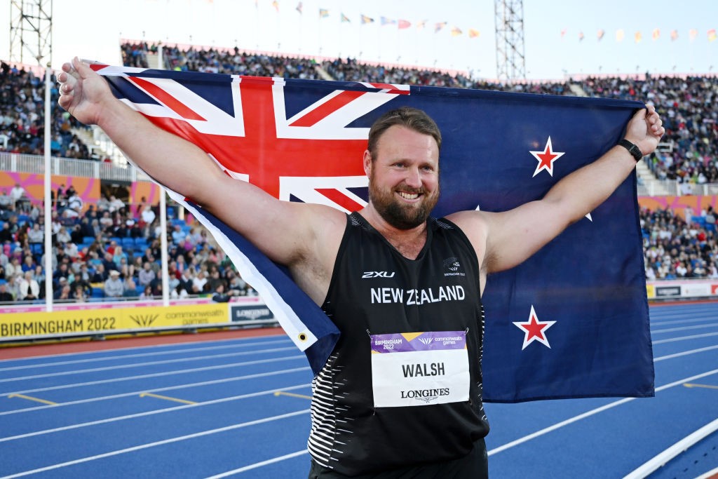 A man holds a New Zealand flag behind his head