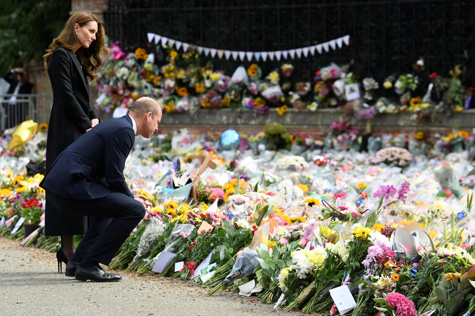 Will bends down to view a bed of flowers as Kate stands beside him.