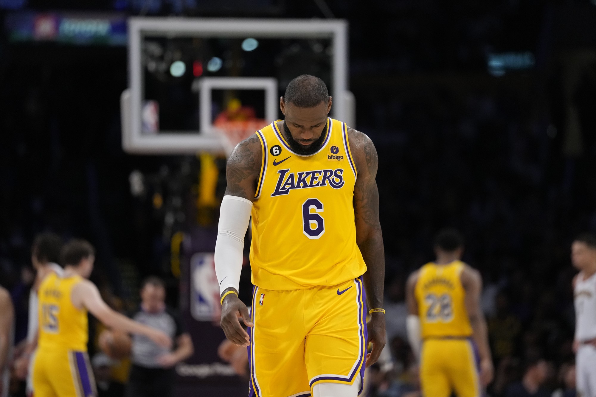Lebron James in his Los Angeles Lakers jersey, walking on a basketball court with his head down