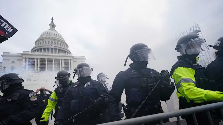People in riot gear outside the US Capitol.