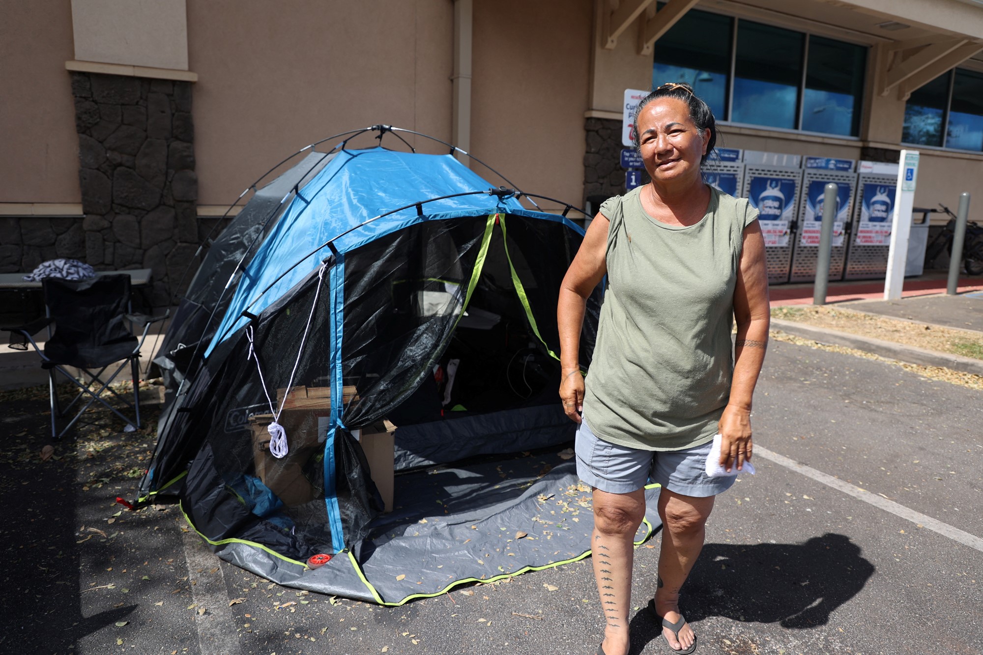 Local resident Uilani Kapu stands in front of her tent in a strip-mall parking lot, as she helps oversee the distribution of donated food, clothing, baby formula and other essentials to neighbors who have lost everything