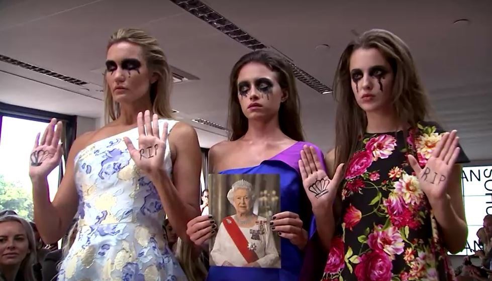 Fashion models stand with smeared eye makeup holding a photo of the Queen with RIP written on their hands.