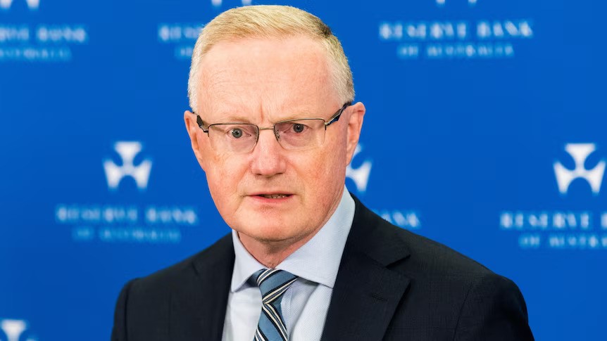 A middle-aged white man with short hair and glasses, wearing a suit