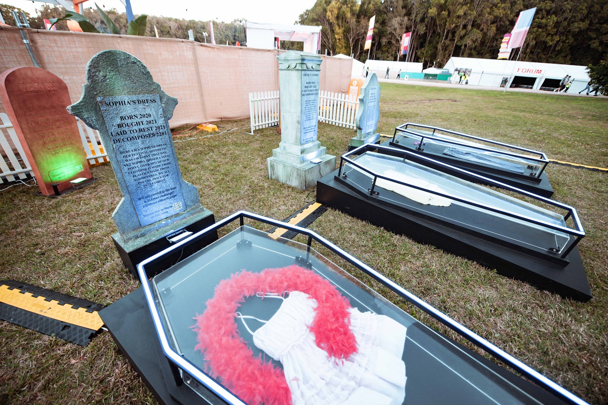 A fake glass coffin with a headstone for a dress and feather boa showing how long they'll take to break down