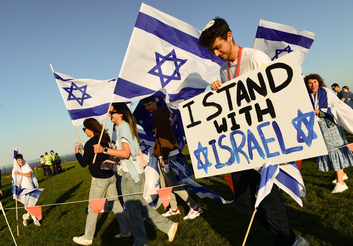 People are pictured carrying Israelian flags and carrying a sign that says 'I stand with Israel' 