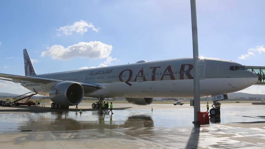 A Qatar Airways plane on a tarmac on a sunny day.