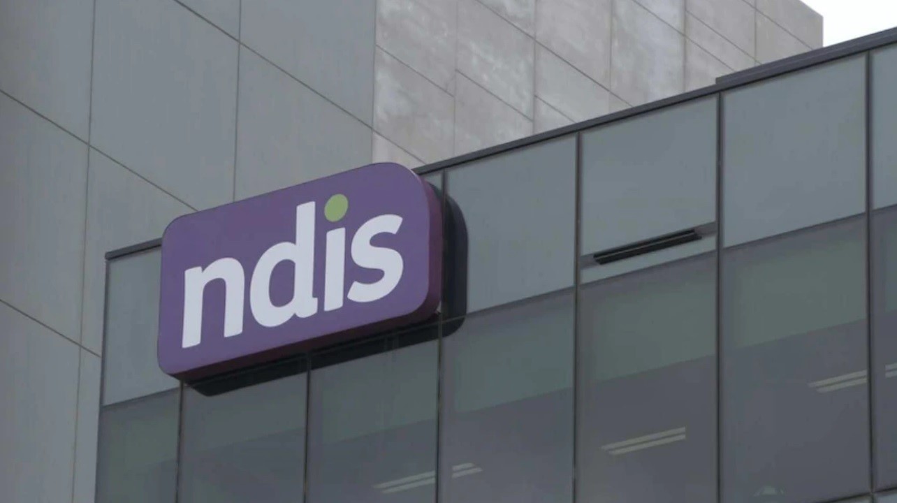 A purple sign on a building says NDIS