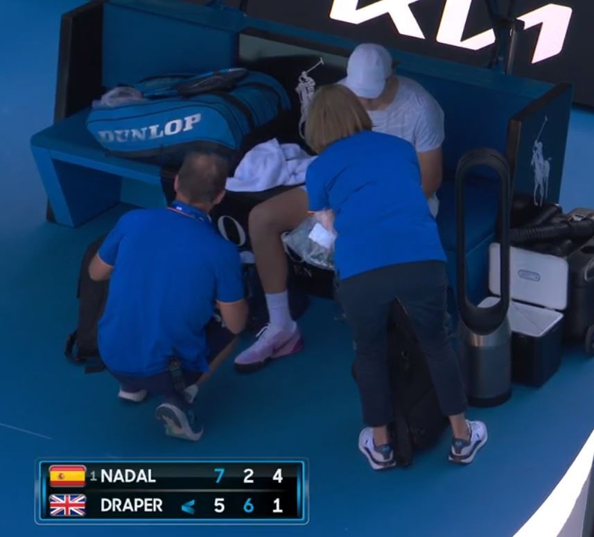 A tennis players is treated by physios.