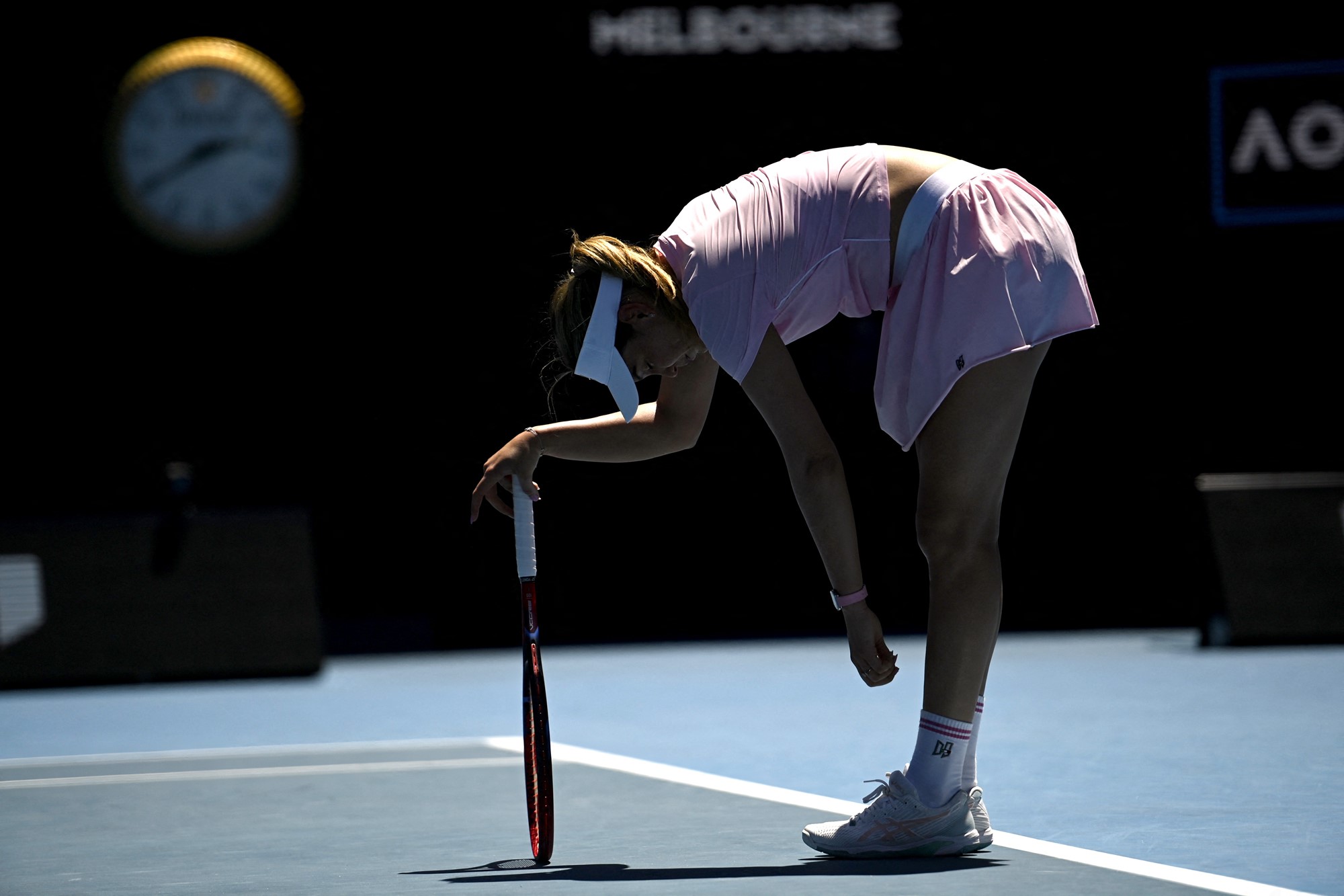 A tennis player leans on her racquet.