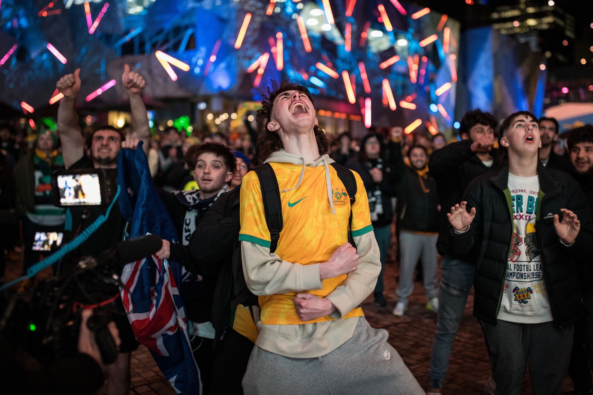 A young man in a Matildas jersey screams in the middle of the crowd.