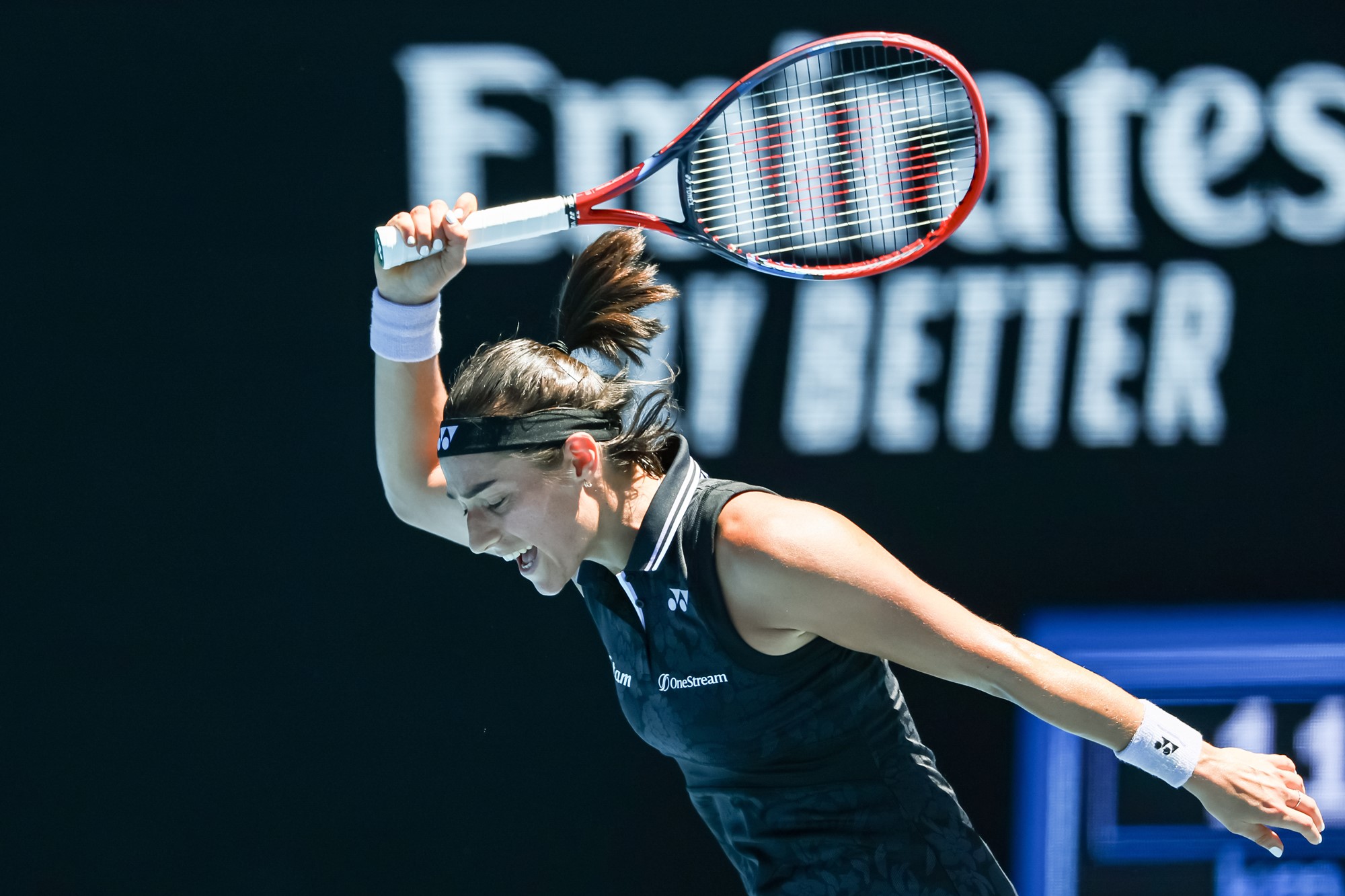 A tennis player gesticulates with her racket.