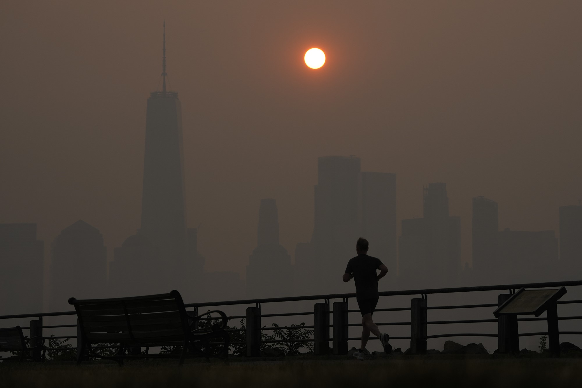 A person seen running, with the New York City skyline behind them in an orange haze