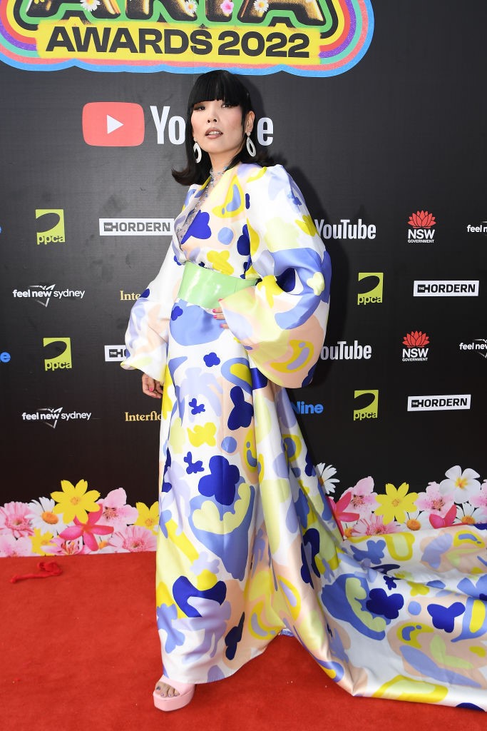 dami im poses on the red carpet in a colorful dress with large sleeves