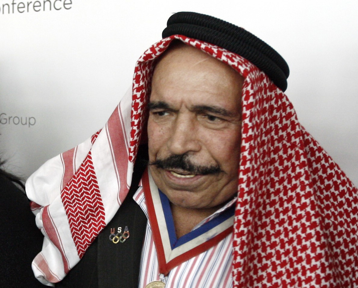 An elderly man with a moustache, wearing a medal around his neck and a head covering