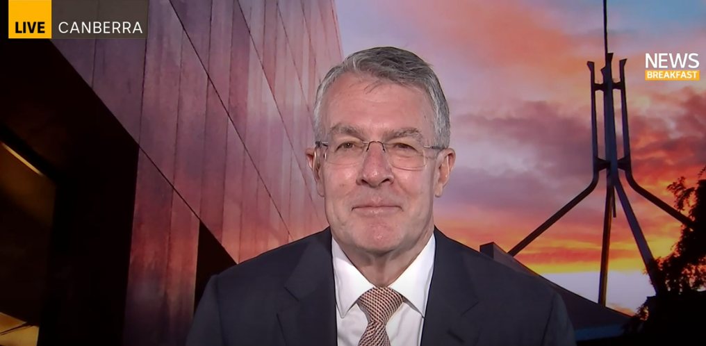Attorney-General Mark Dreyfus sits in a suit in front of a parliament house interview backdrop on ABC News Breakfast