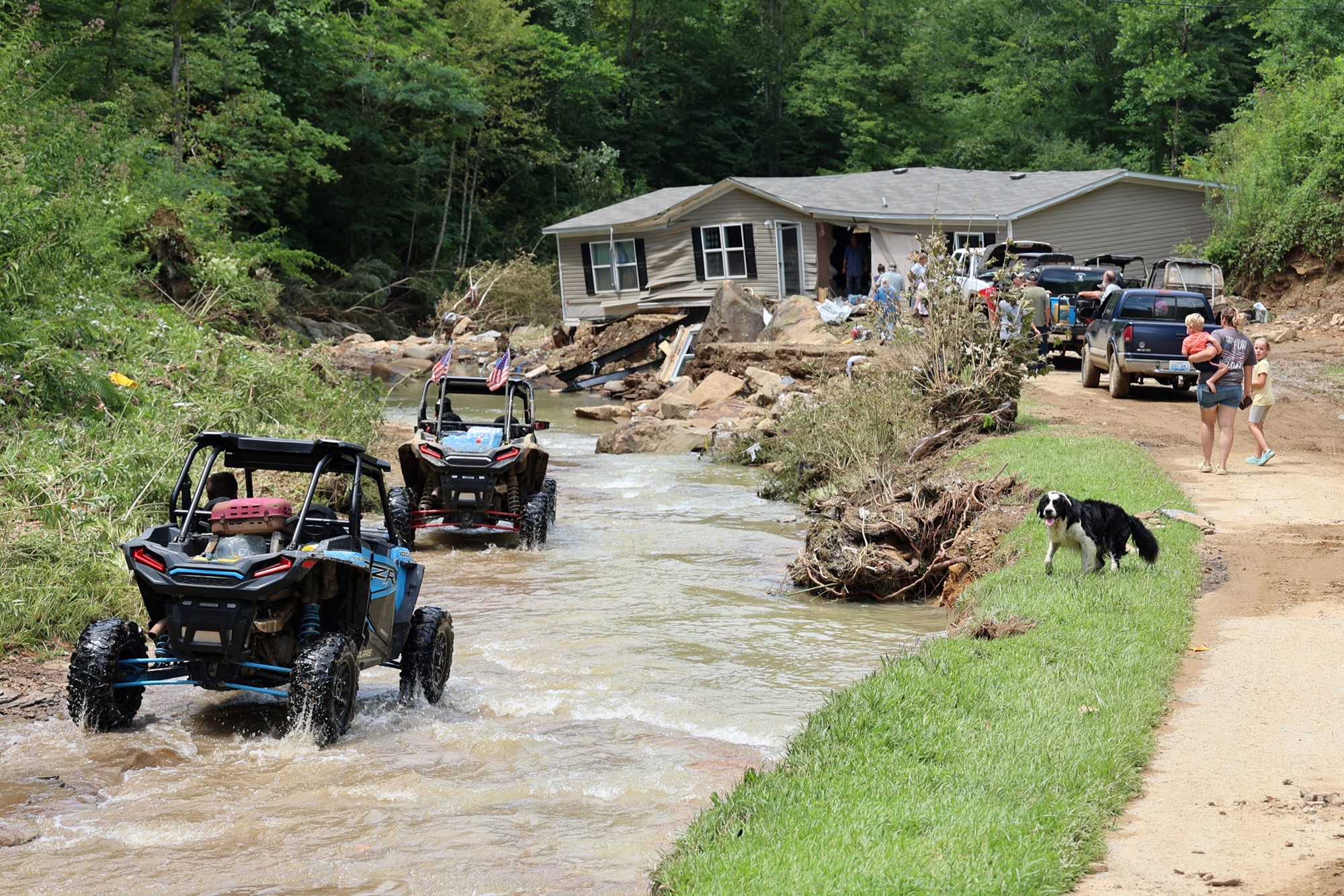 Two ATV's drive through water twards a house