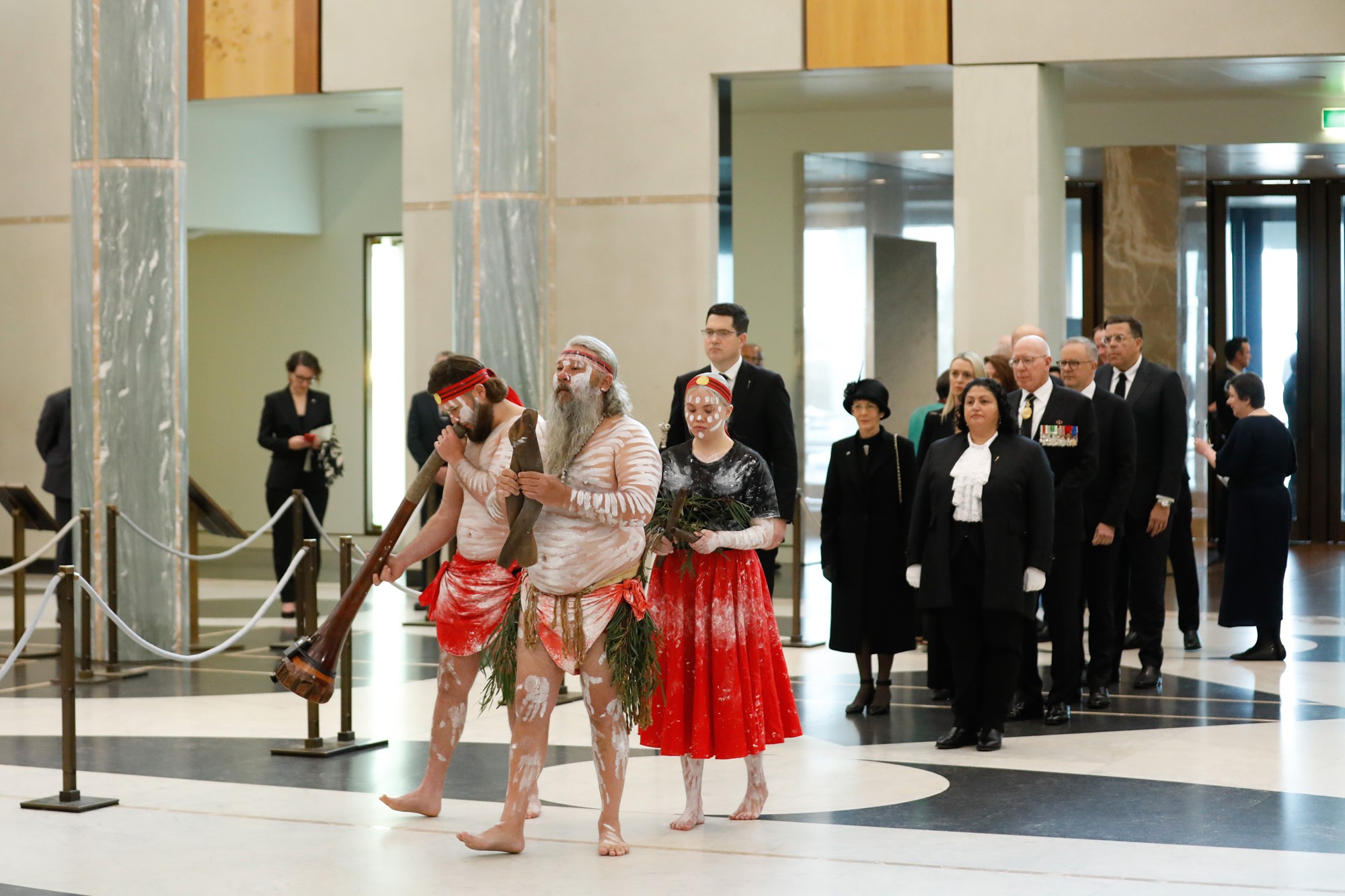 Indigenous dancers walk through Parliament House.