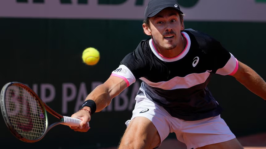 A male tennis player lunges to hit a ball during a game