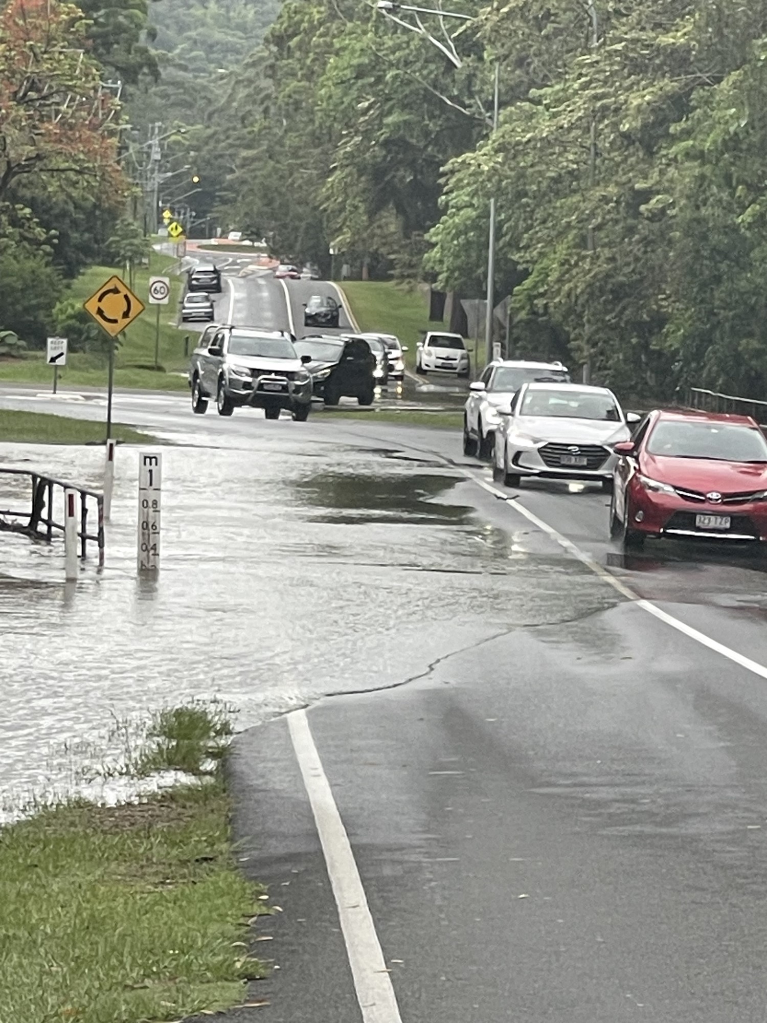 Cars drive over a partially flooded road