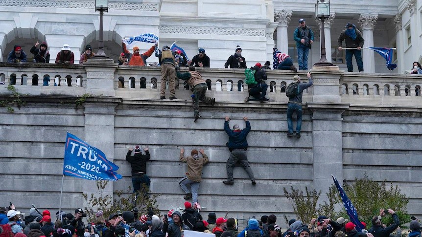 People scale a wall during the US Capitol riot.