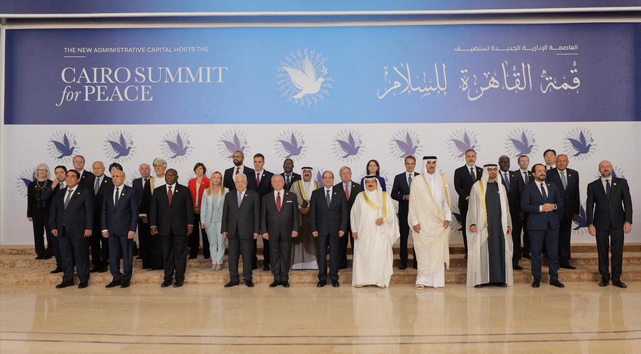 A large group photo of leaders in front of sign saying cairo summit for peace