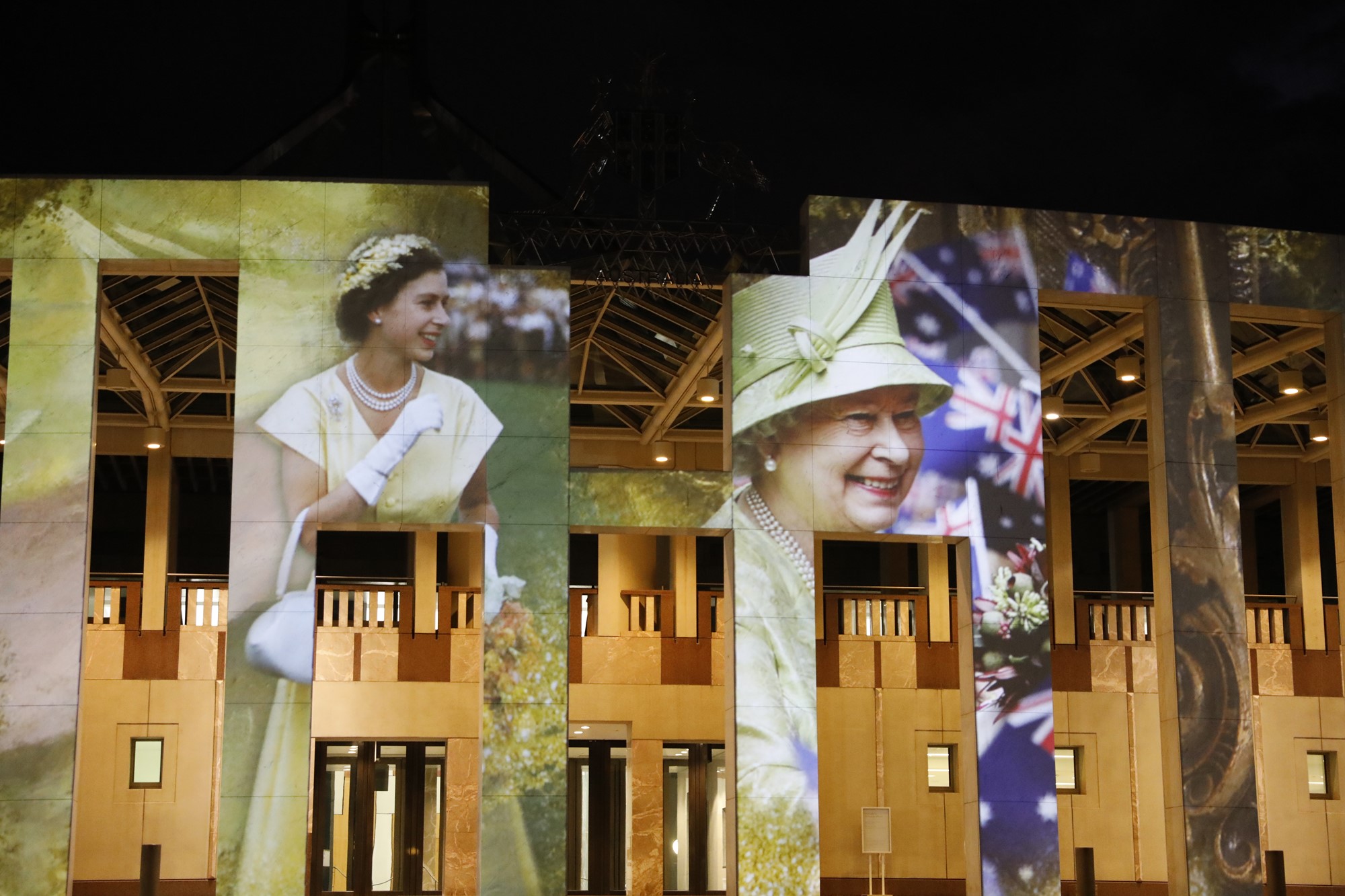A projection on Parliament House shows a young Queen Elizabeth II and an older Queen Elizabeth II.