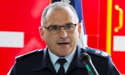 A man in a suit and tie, standing at a podium, speaking into a microphone