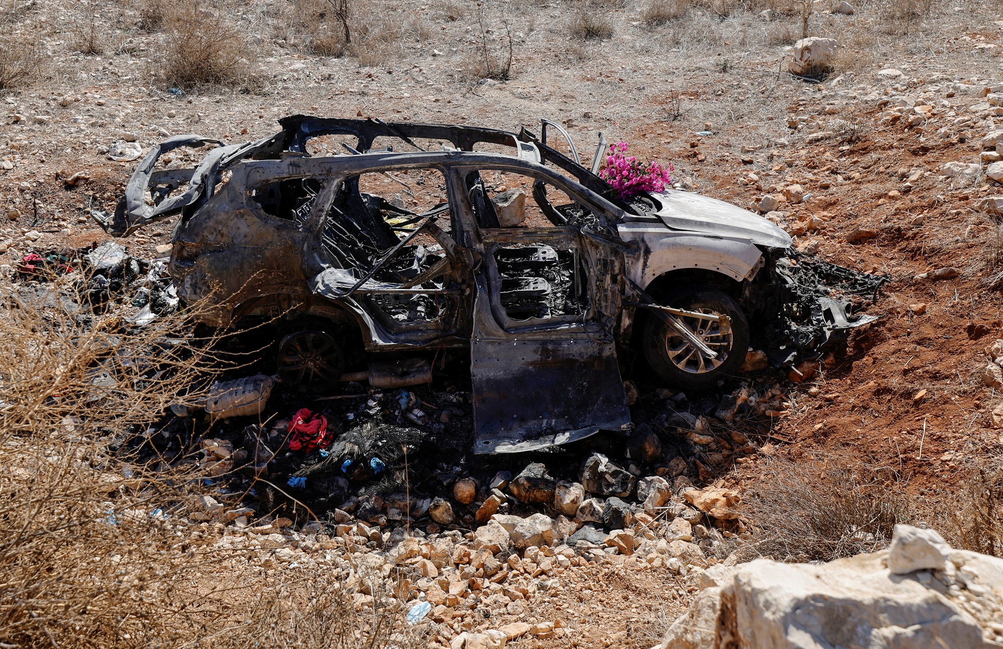 A burnt car wreck in a dry landscape