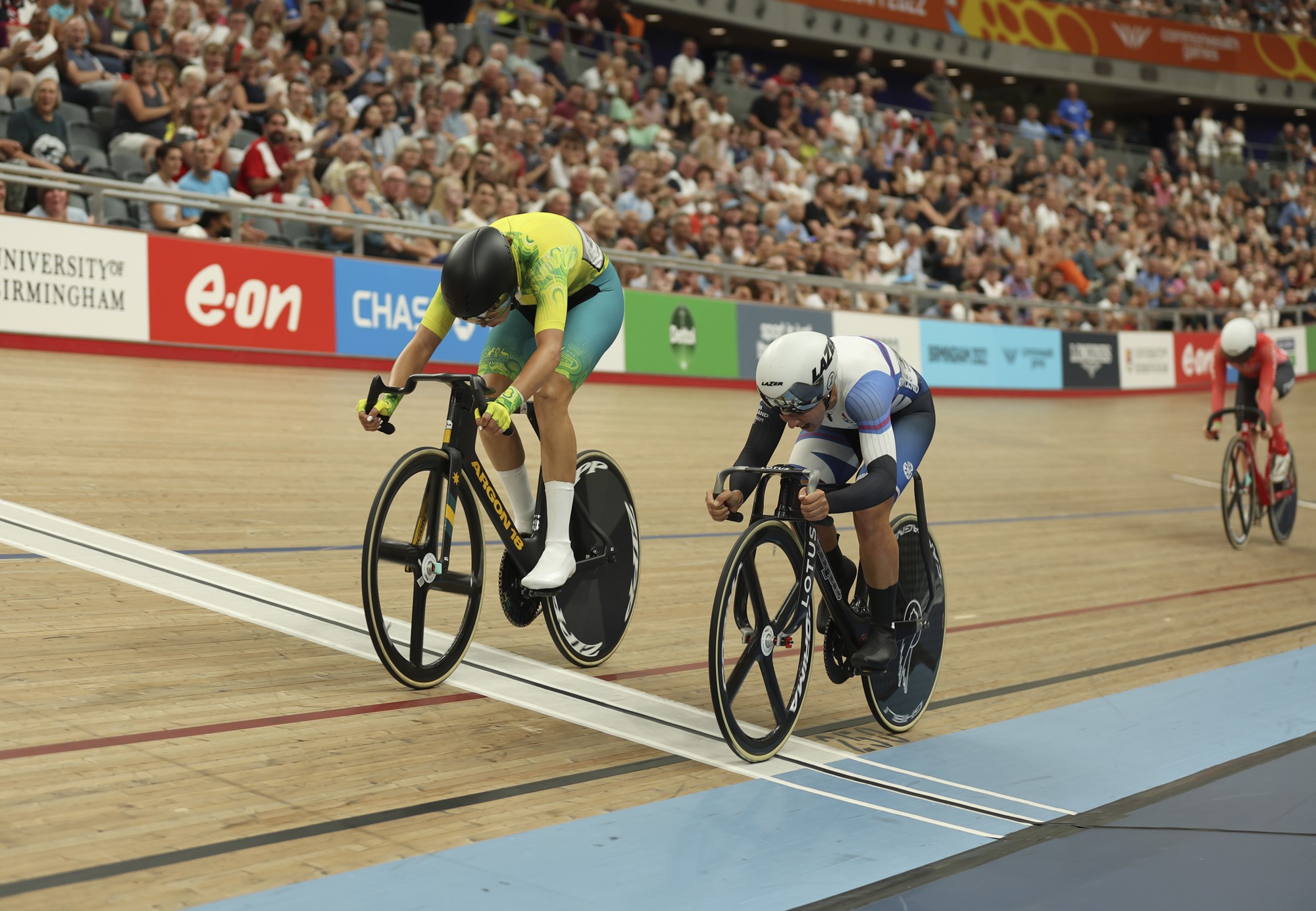 An Australian cyclist puts her head down and pedals over the line in the velodrome ahead of a Scottish rival