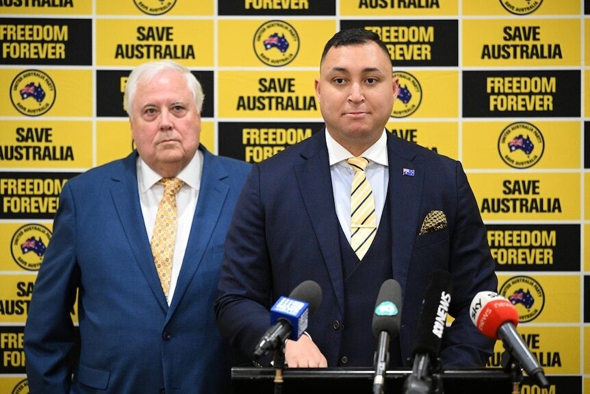 Clive and Ralph front a press conference with a yellow party background.
