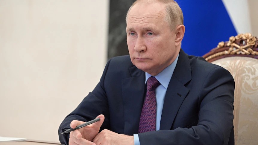 Vladimir Putin sitting at a table wearing a suit
