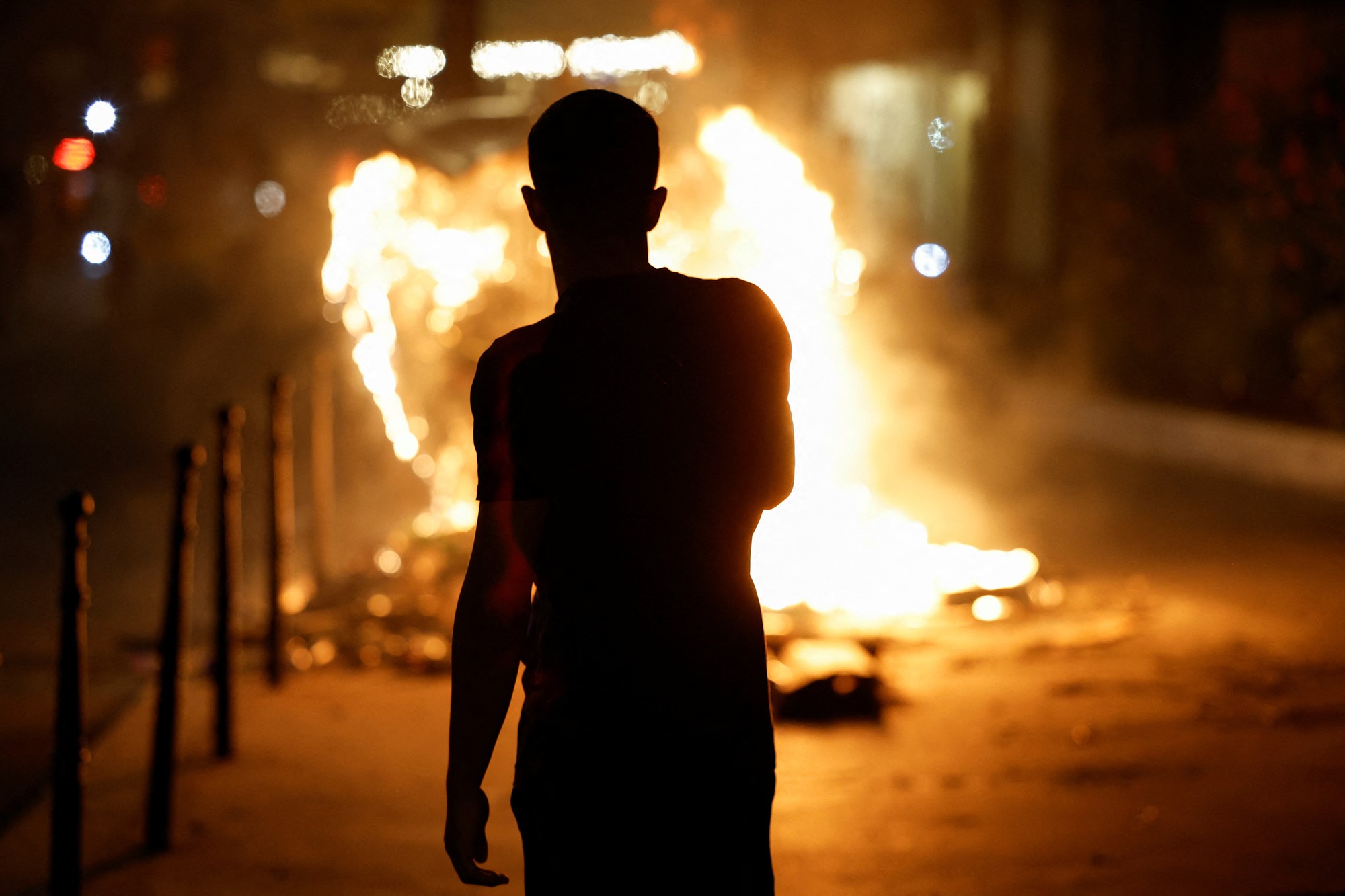 A person stands near a burning container