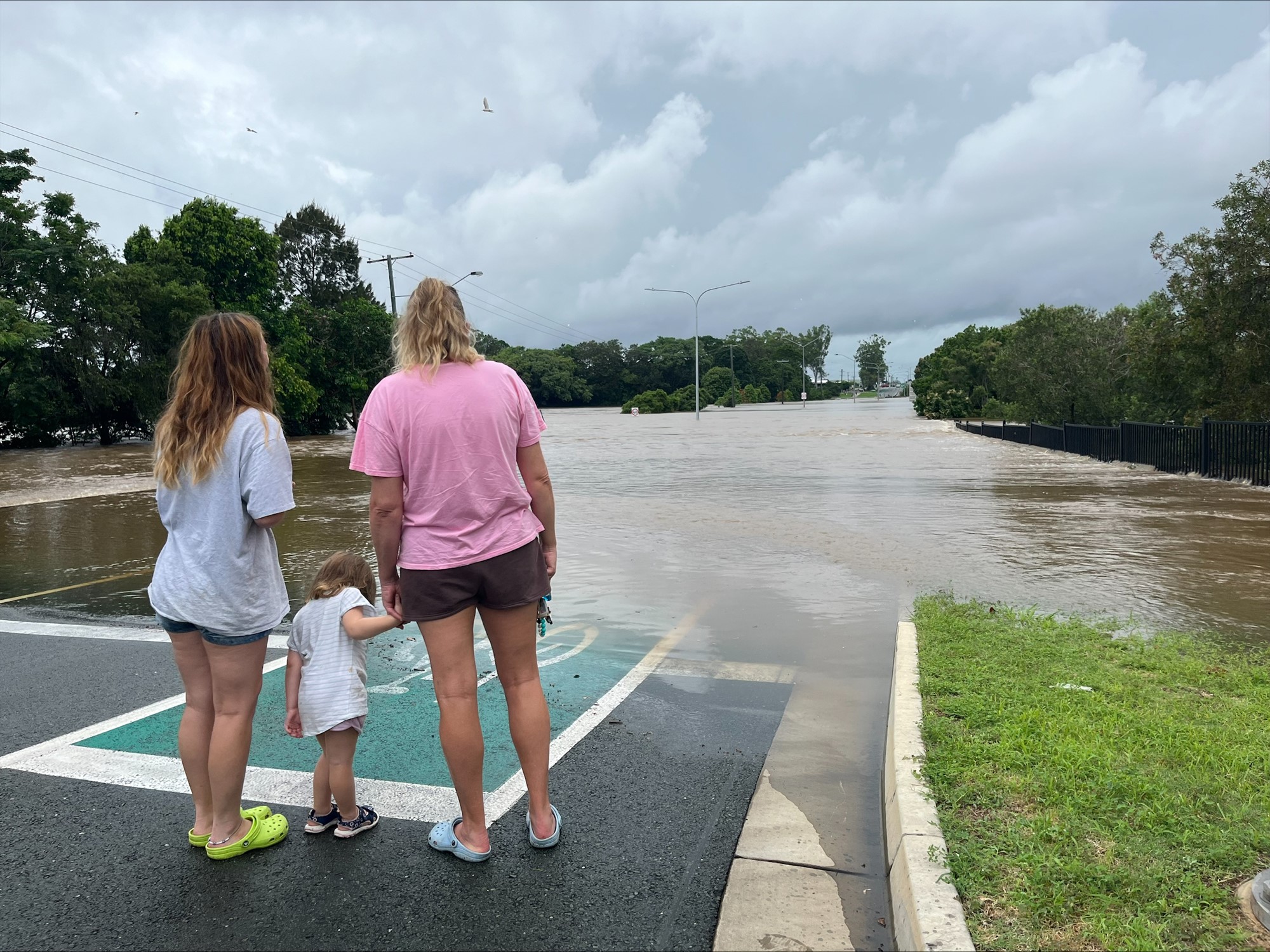 A woman and two children looking at flooding over a main road