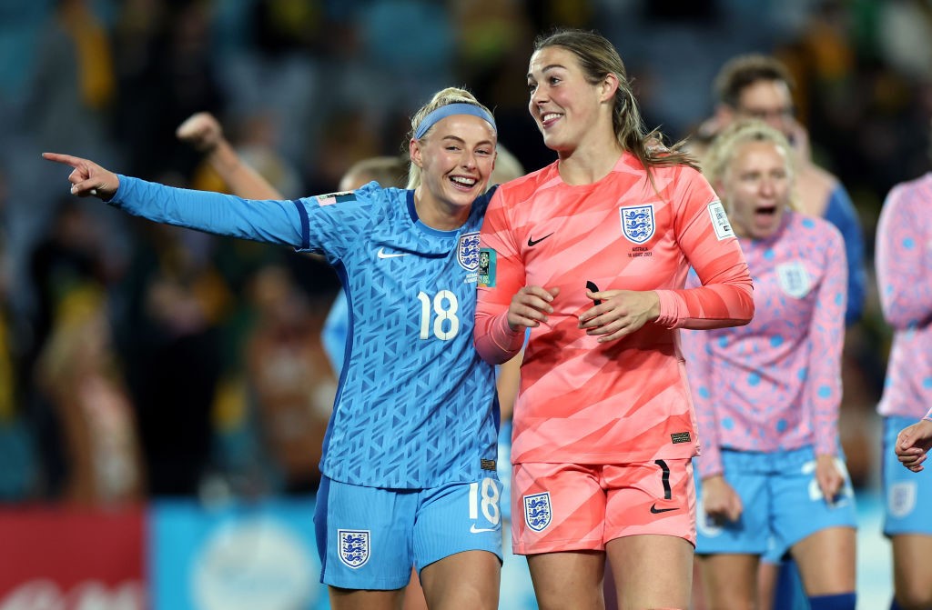 Chloe Kelly points and laughs as she walks with England goalkeeper Mary Earps.
