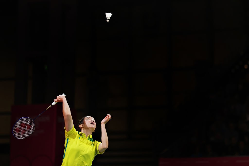 A badminton player lines up a serve with the shuttle cock high in the air