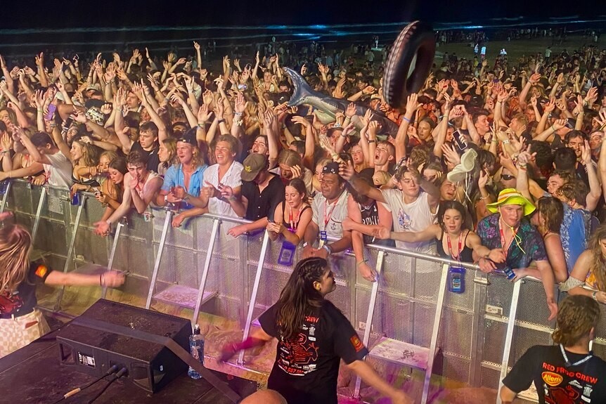 A large party crowd waving their arms in the air