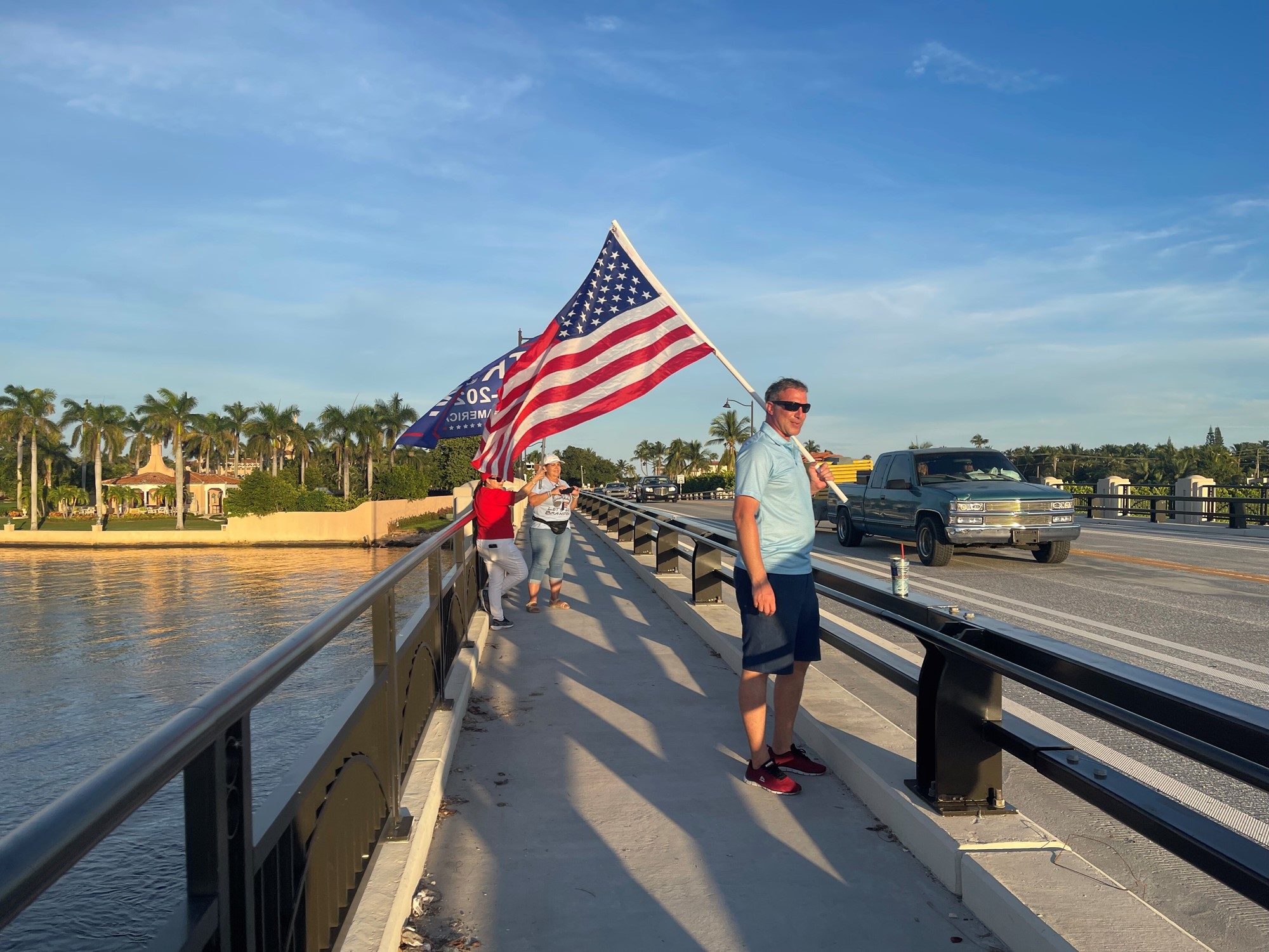 Man holds Trump 2024 USA flag near the beach.