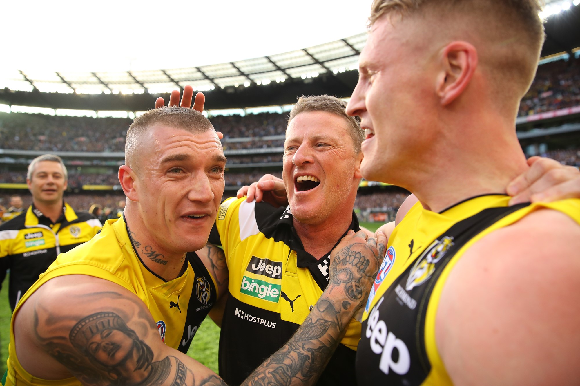 Coach Damien Hardwick celebrates with Richmond players Dustin Martin and Josh Caddy on the MCG after the 2017 grand final win over Adelaide 