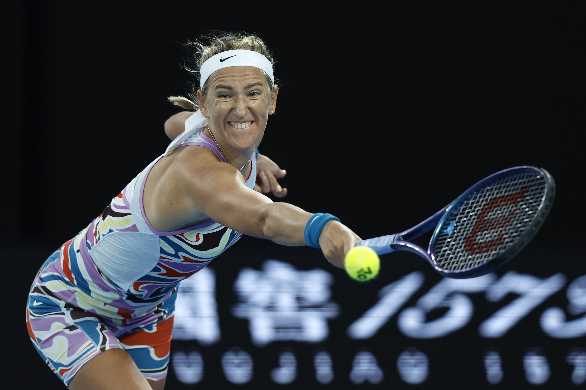 A tennis player stretches to hit a backhand.