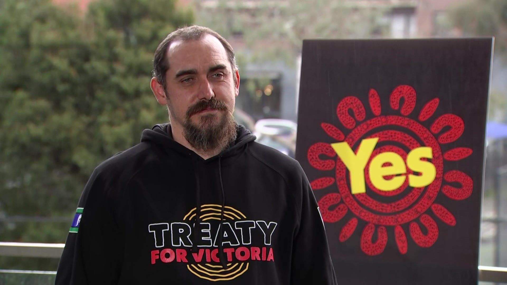 A young Aboriginal man in a black hoodie with the words "Treaty for Victoria".