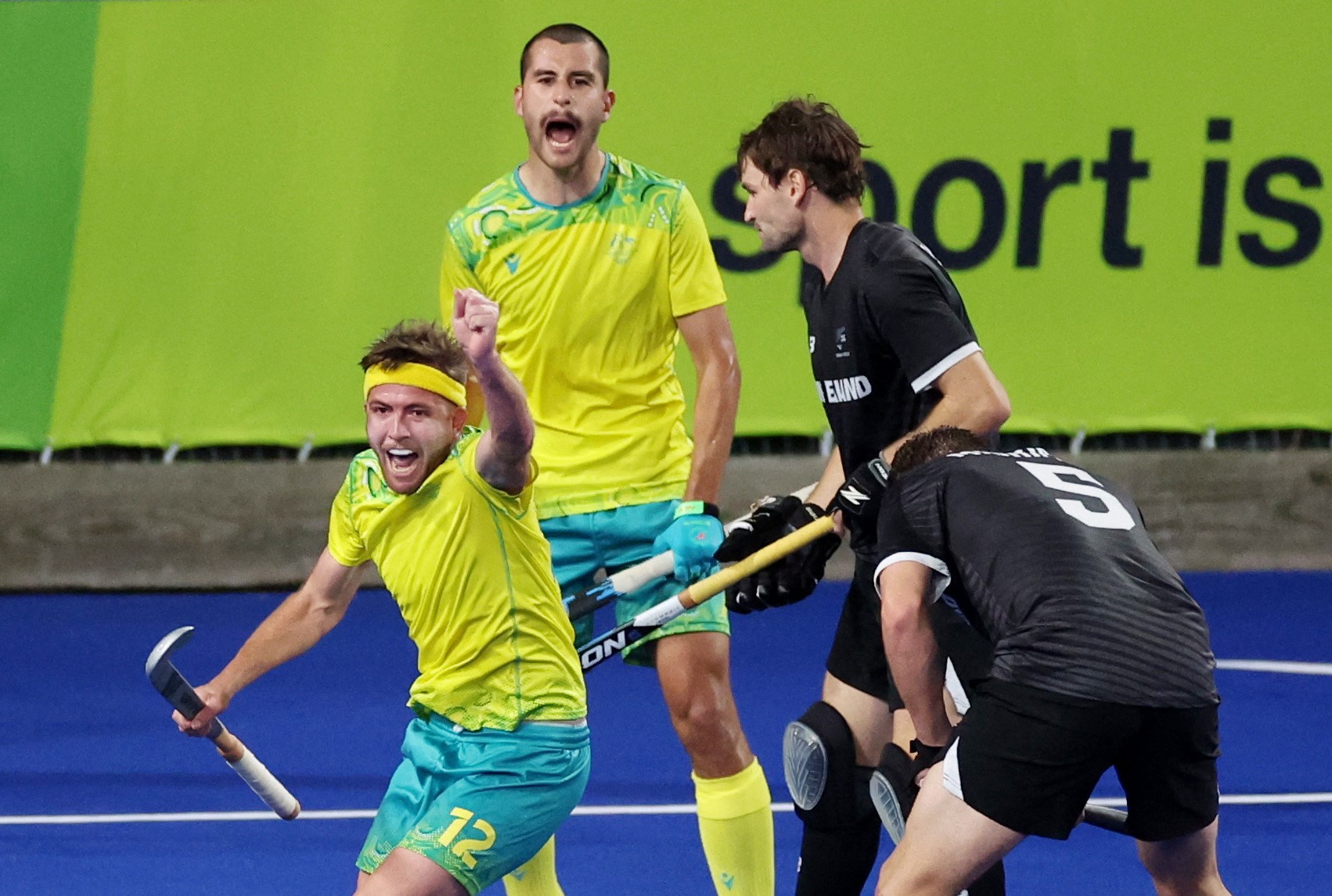 australian hockey players celebrate while new zealand players look defeated during a match