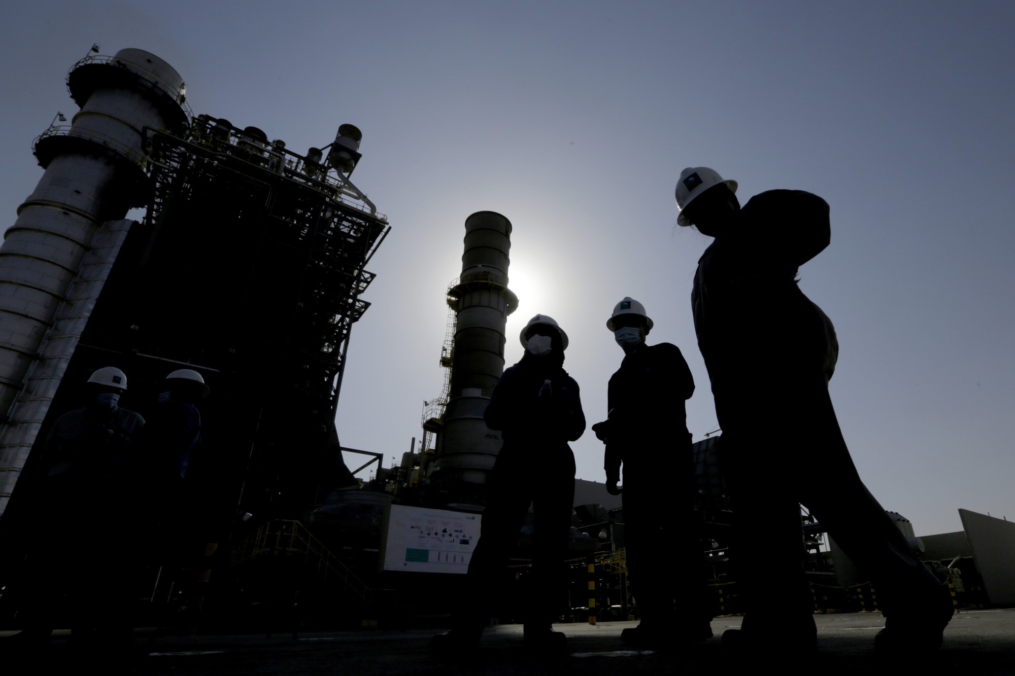 Saudi Aramco engineers walk in front of a gas turbine generator at Khurais oil field
