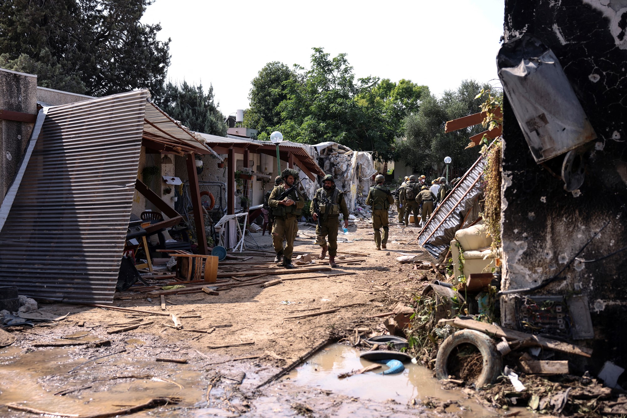 A group of soldiers walking through a damaged area. 
