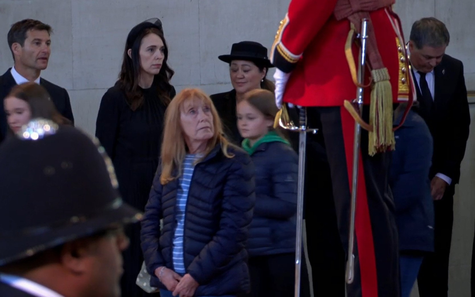 A woman dressed in all black stands solemnly.