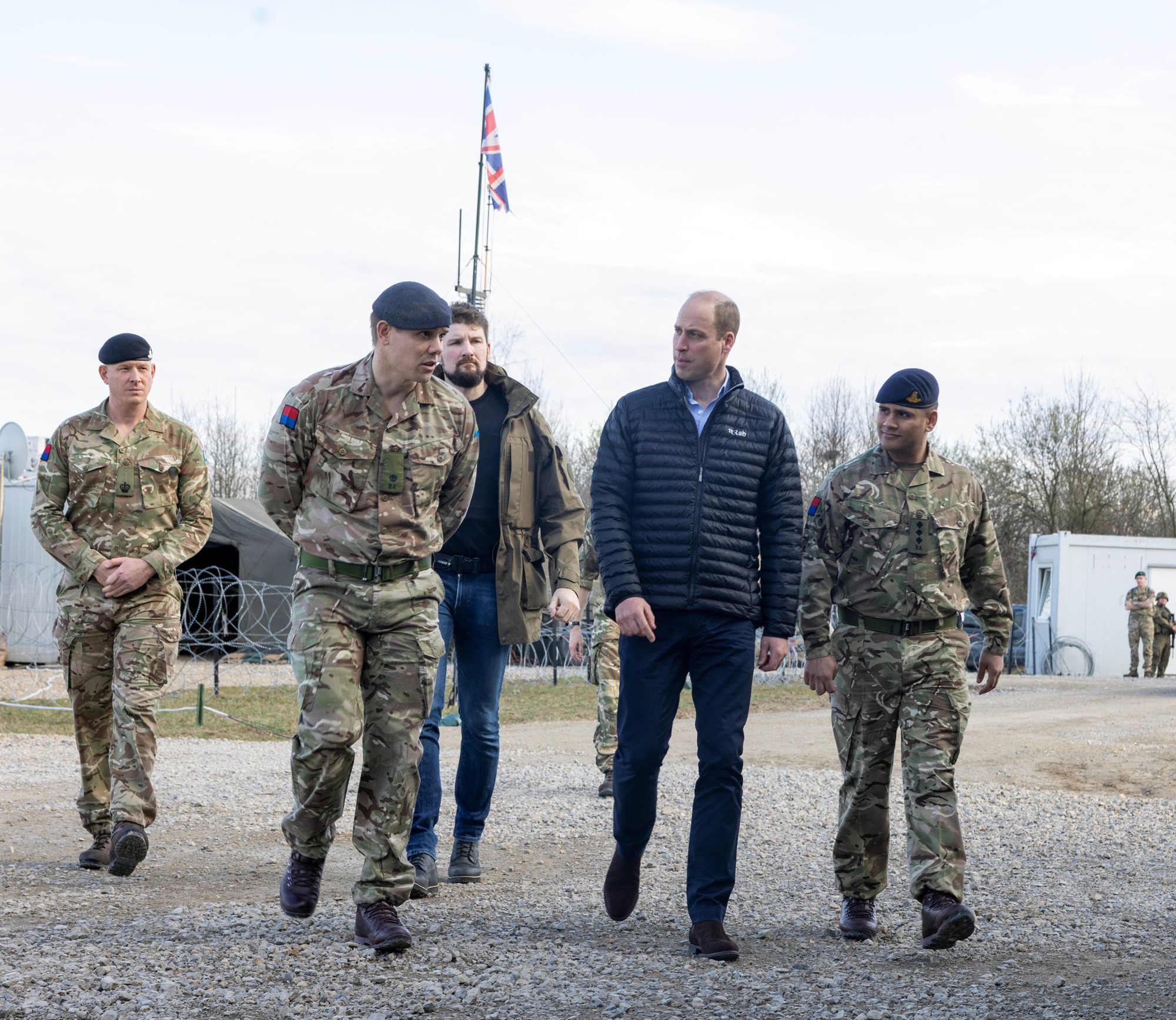 Prince William walks with men in military uniform. 