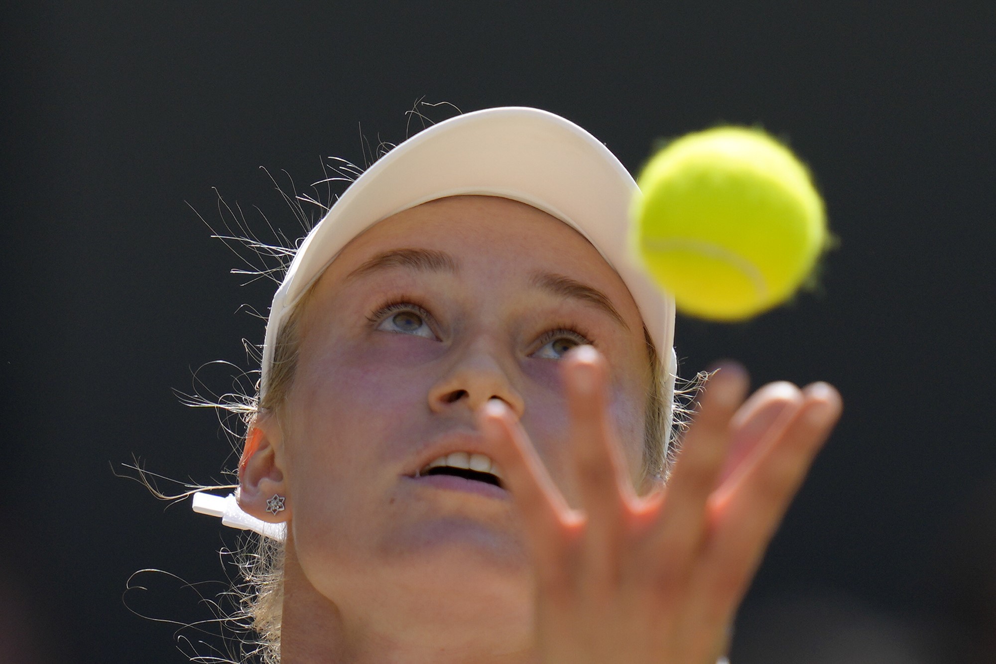 Elena Rybakina throws a tennis ball in the air for her serve in the Wimbledon final.