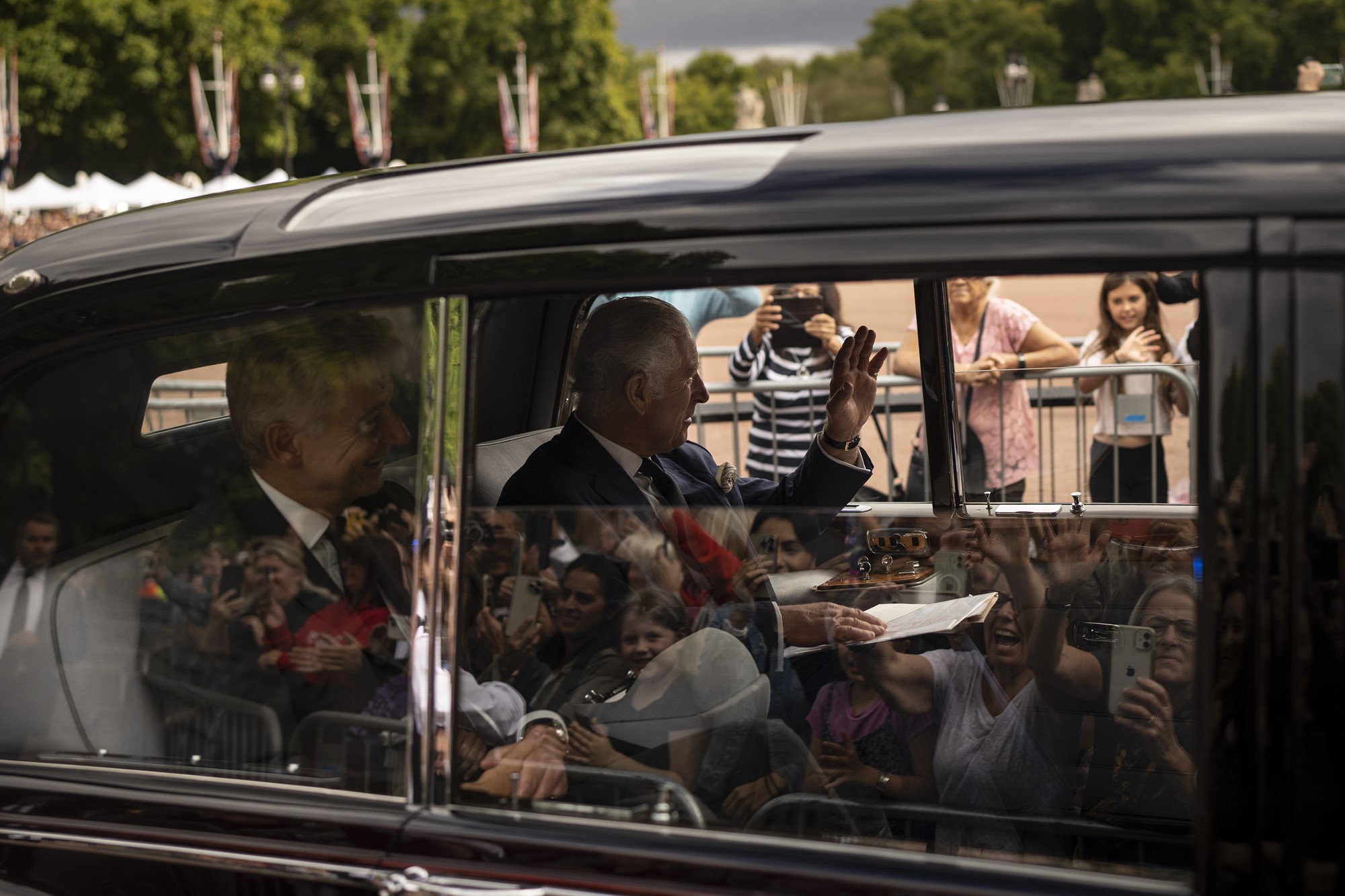 King Charles III greets supporters from a car as he arrives to Buckingham Palace