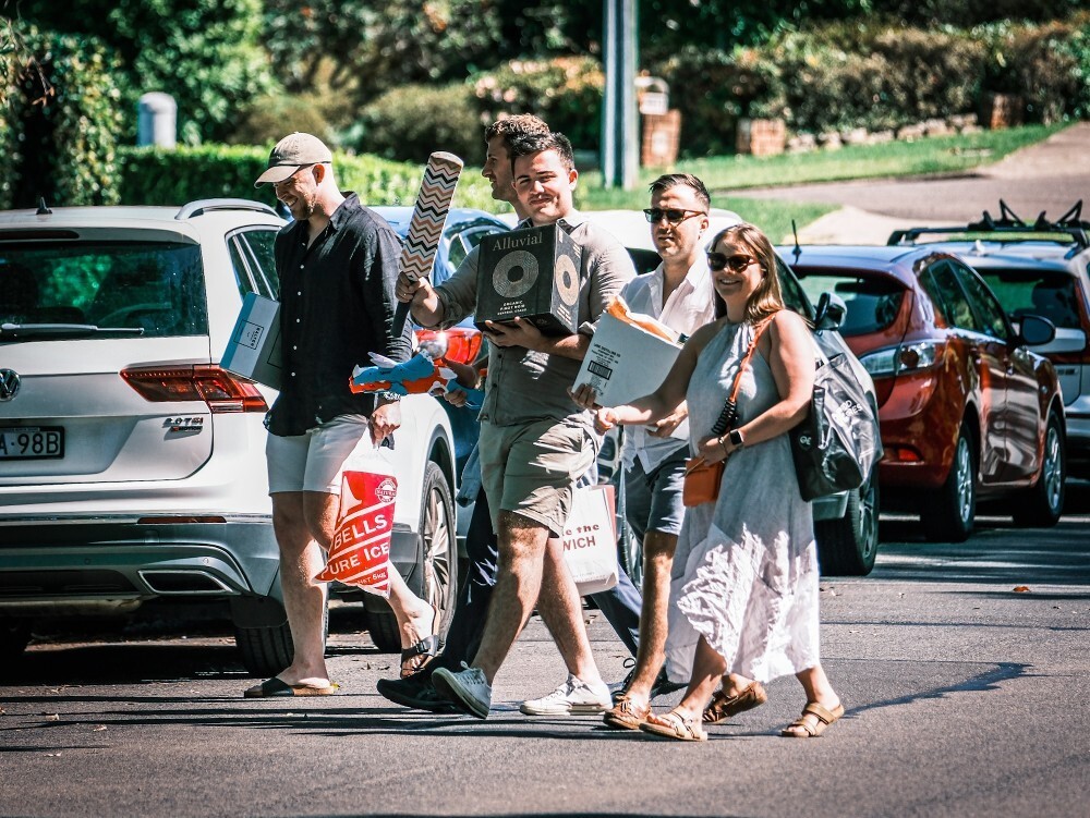 A group of people walking, carrying drinks.