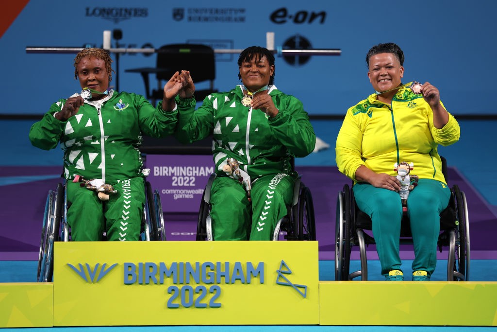 Three women in wheelchairs hold up medals