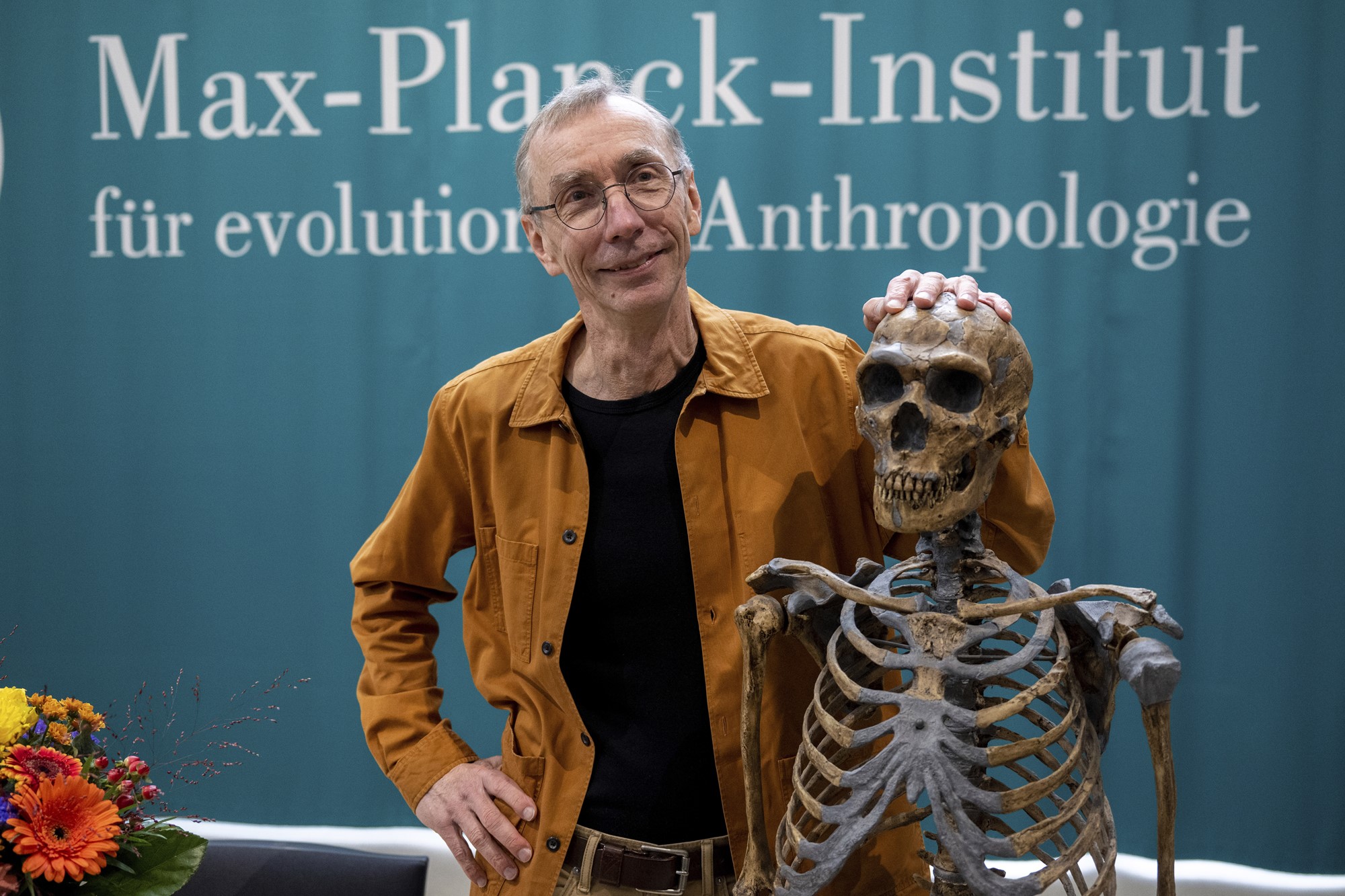 Svante Paabo stands by a replica of a Neanderthal skeleton